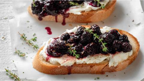 Zwei Ziegenkäse-Stullen mit geschmolzenen Brombeeren auf einem Tisch