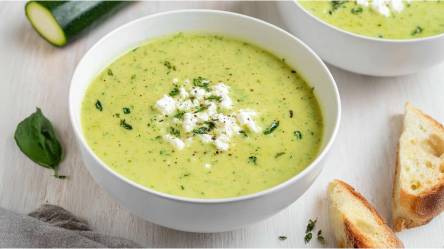 Schale mit Zucchini-Feta-Suppe, Baguettescheiben daneben
