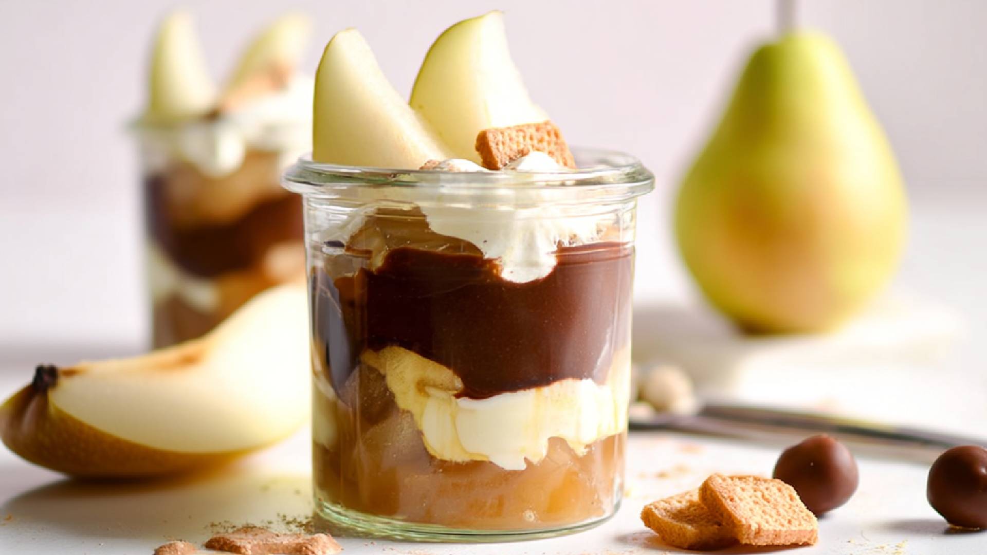 Zwei Gläser Birne Helene Trifle auf einem Tisch, frische Birnen im Hintergrund