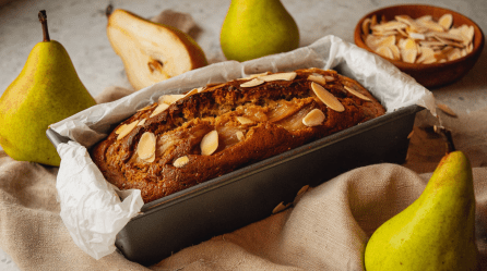 Birnen-Mandel-Kuchen aus der Kastenform, daneben frische Birnen.