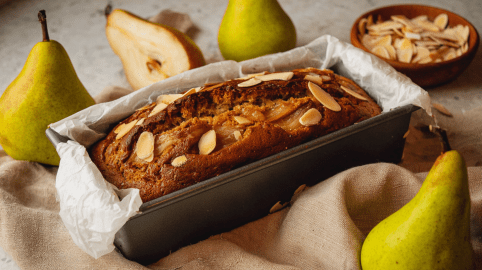 Birnen-Mandel-Kuchen aus der Kastenform, daneben frische Birnen.