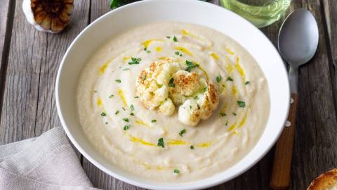 Eine Schüssel mit Blumenkohl-Bohnen-Suppe, garniert mit geröstetem Blumenkohl.