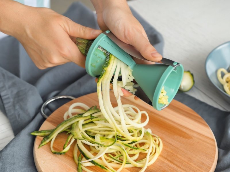 Gemüse schneiden: EIne person bereitet Zucchinispaghetti in einem Gemüseschneider zu.