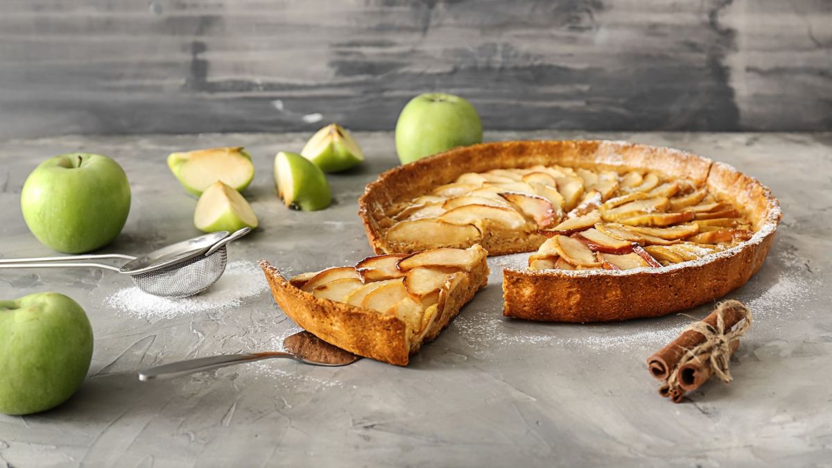 Eine Haferflocken-Apfel-Tarte mit einigen Äpfeln auf einer Arbeitsfläche.