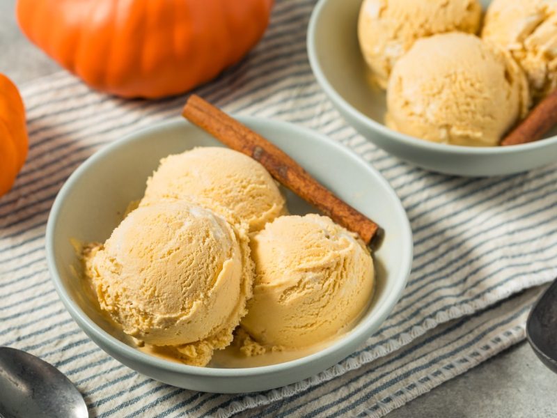 Zwei Schüsseln Kürbis-Eis, daneben mehrere Kürbisse.