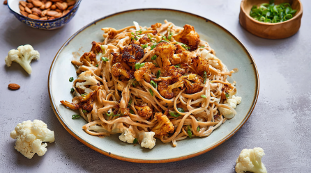 Ein Teller Nudeln mit Blumenkohl und Erdnussbutter.