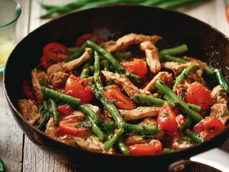 Putengeschnetzeltes mit Bohnen und Tomaten in einer Pfanne.