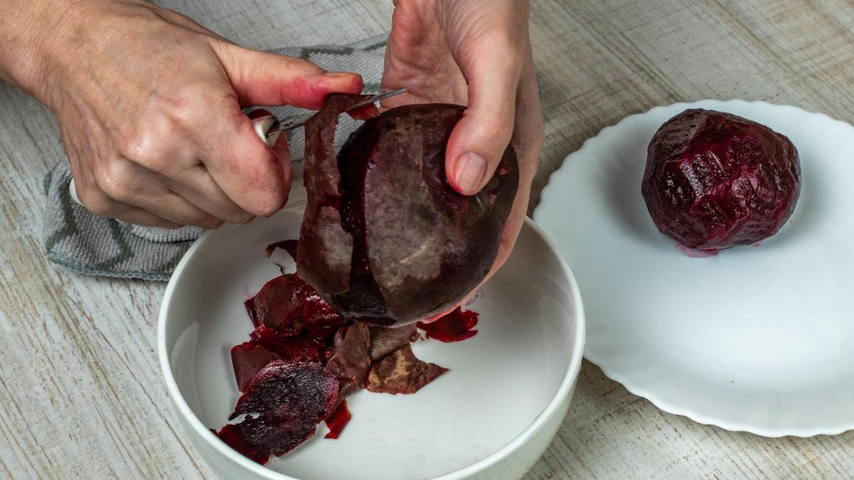 Rote Bete schälen: Eine Person schält eine Rote Bete mit einem Messer.