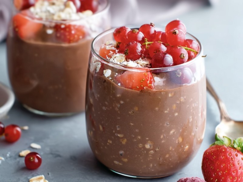 Zwei Gläser Schokopudding-Oats mit frischen Beeren.