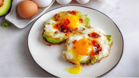 Teller mit zwei Avocado-Toast mit Ei und Crispy Chili Oil