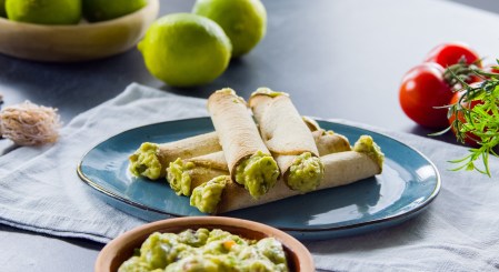 Mehrere Tortilla-Wraps mit Guacamole übereinander gestapelt auf einem Teller.