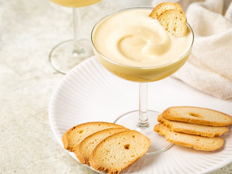 Ein Glas Zabaione: italienische Dessertcreme, serviert mit Keksen.