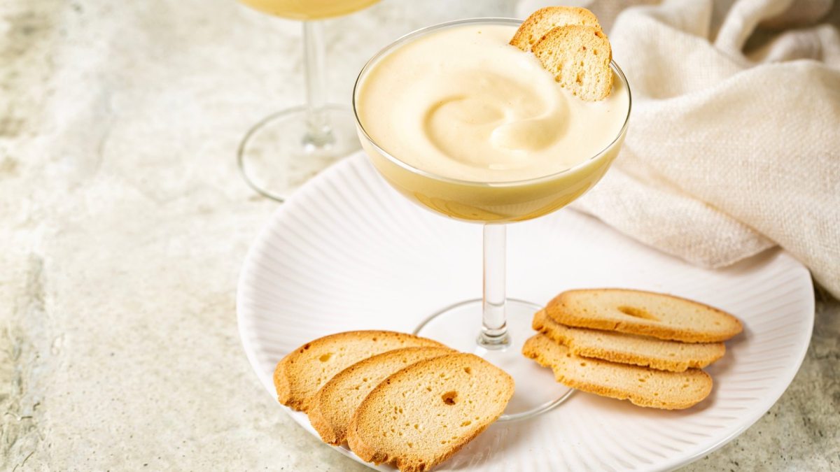 Ein Glas Zabaione: italienische Dessertcreme, serviert mit Keksen.