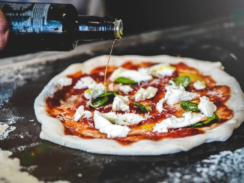 10 Fakten über Pizza: Pizzabäcker beim Zubereiten einer Pizza