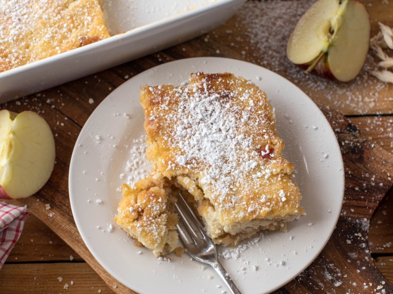 Ein Stück Apfel-Hirse-Auflauf mit einer Gabel auf einem Teller.