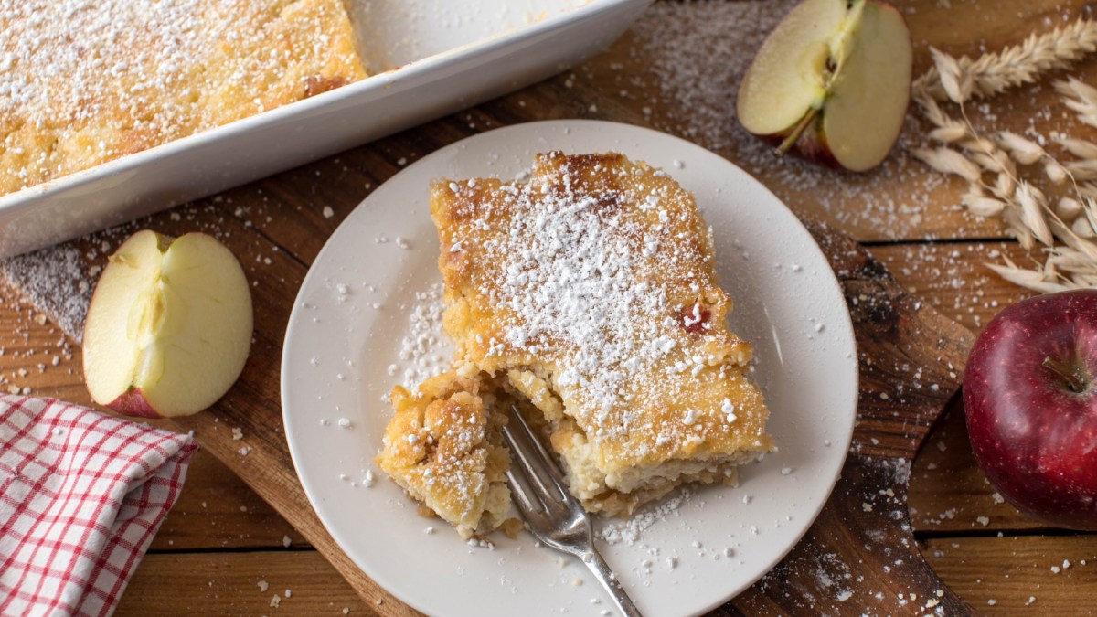 Ein Stück Apfel-Hirse-Auflauf mit einer Gabel auf einem Teller.