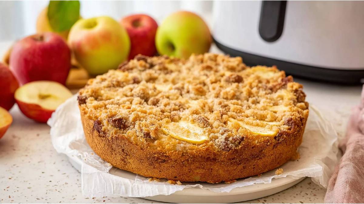 Ein gebackener Apfel-Streuselkuchen aus dem Airfryer, Äpfel und Airfryer im Hintergrund