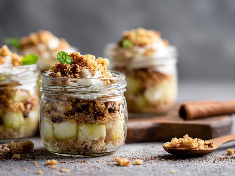 mehrere Gläser mit Apple Crumble im Glas auf einem Tisch