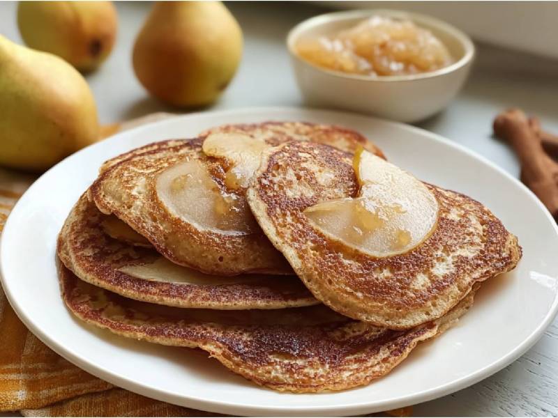 Teller mit mehreren Birnen-Pancakes, Birnen und ein Schälchen mit Birnenmus im Hintergrund