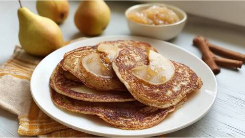 Teller mit mehreren Birnen-Pancakes, Birnen und ein Schälchen mit Birnenmus im Hintergrund