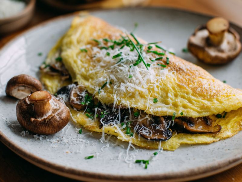 Champignon-Omelett mit Bergkäse auf einem weißen Teller.