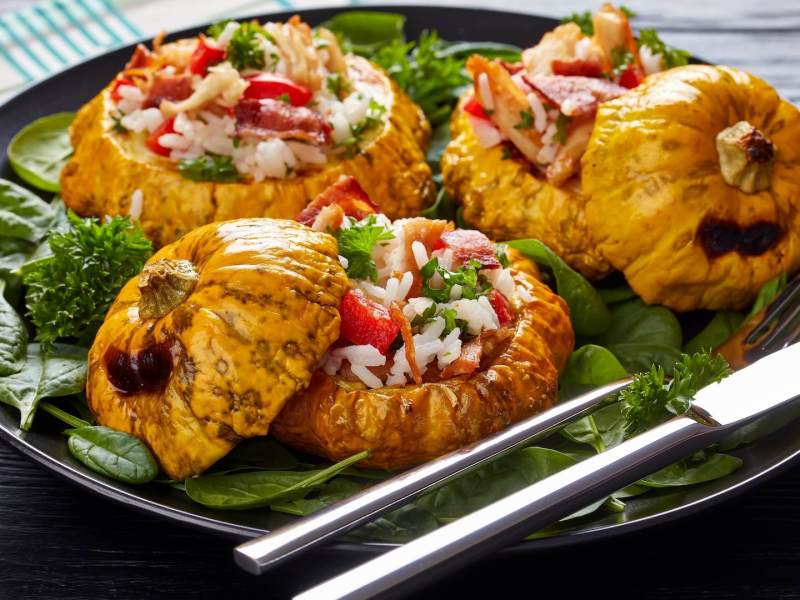 Gefüllter Patisson mit Reis auf einem dunklen Teller.