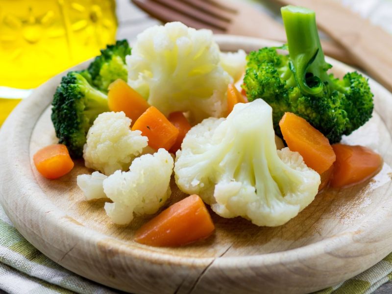 Gemüse dämpfen: Etwas gedämpftes Gemüse auf einem Holzbrett.