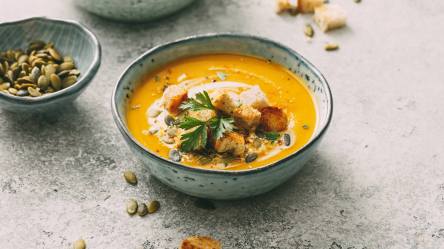 Eine Schüssel Kürbis-Petersilienwurzel-Suppe, garniert mit Croûtons.