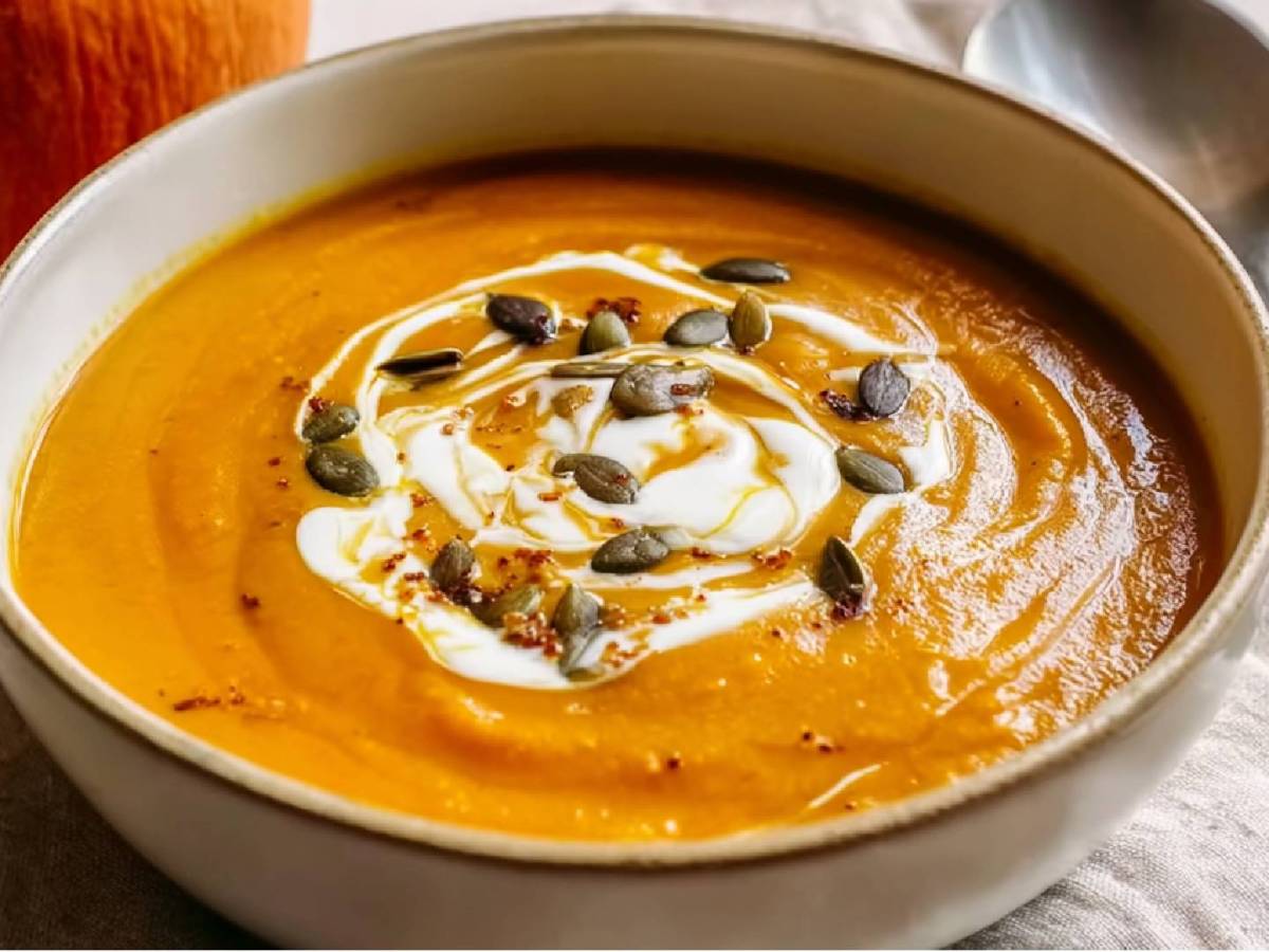 Eine Schale mit Sanddorn-Kürbis-Suppe mit Kokosmilch und Kürbiskernen verziert