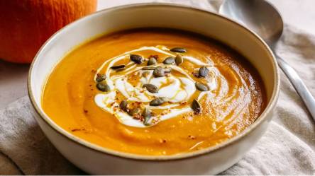 Eine Schale mit Sanddorn-Kürbis-Suppe mit Kokosmilch und Kürbiskernen verziert