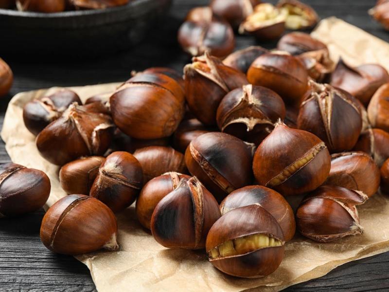 Maronen schneiden: Einige geröstete Maronen auf einem Pergamentpapier.