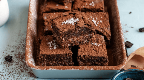 Milchreis-Brownies in einer kleinen Form. Sie sind mit Kakaopulver und etwas grobem Salz bestreut.