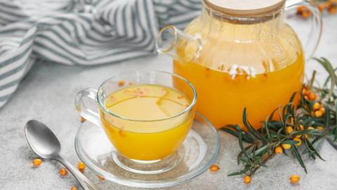 Kanne und Tasse mit Sanddorn-Tee