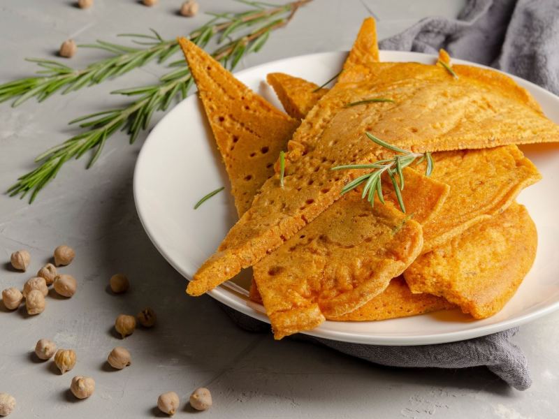 Einige Stücke Socca auf einem weißen Teller.