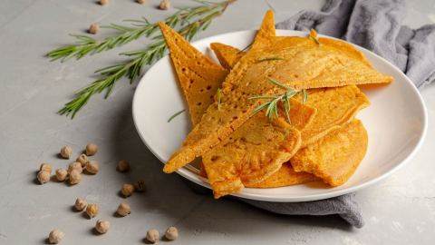 Einige Stücke Socca auf einem weißen Teller.