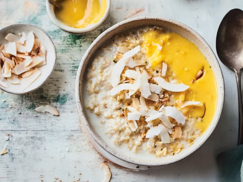 Eine Schüssel White Choc Porridge mit Kokos-Mango-Topping.