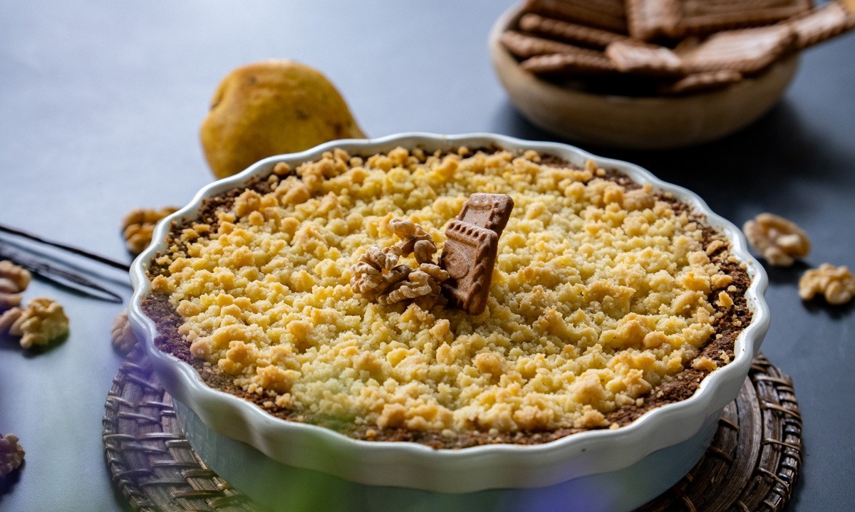 Eine Tarteform mit Birnen-Crumble mit Ziegenkäse garniert mit Walnüssen und Karamell-Keksen.