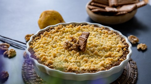Eine Tarteform mit Birnen-Crumble mit Ziegenkäse garniert mit Walnüssen und Karamell-Keksen.