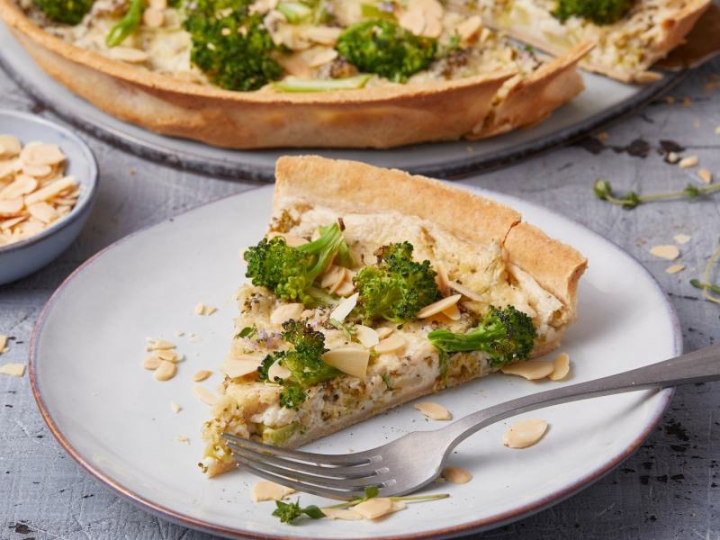 Ein Stück Brokkoli-Hähnchen-Quiche auf einem hellen Teller.