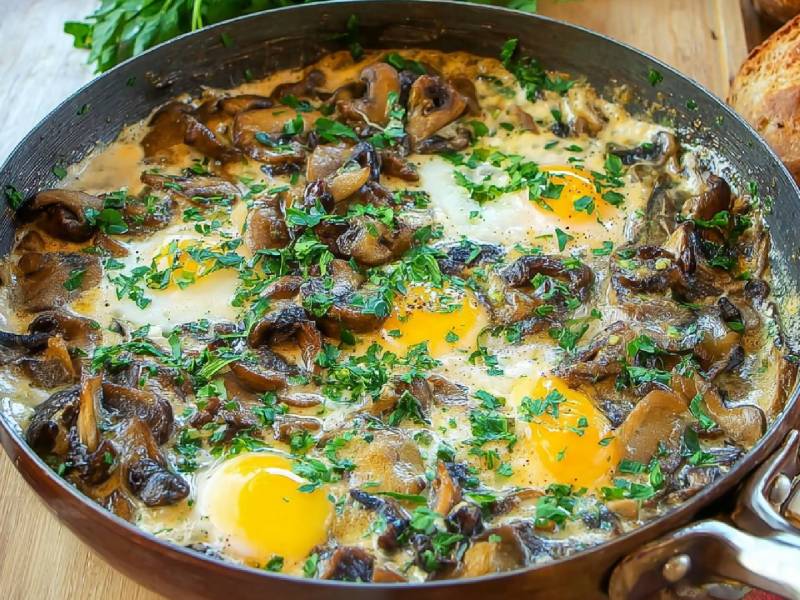 Pfanne mit Champignon-Shakshuka, geröstetes Brot und frische Champignons daneben