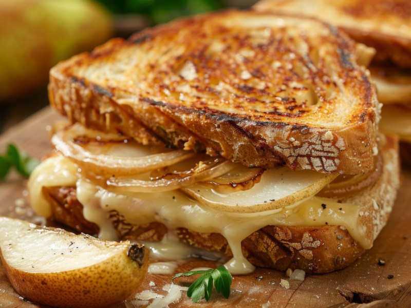Ein grilled Cheese Sandwich mit Birne auf einem Holzbrett