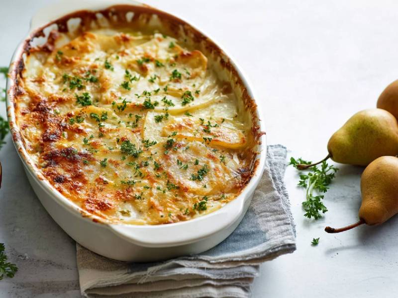 Auflaufform mit Kartoffel-Birnen-Gratin, Birnen daneben