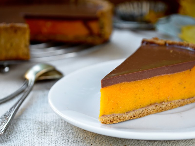 Ein Teller mit einem Stück Kürbis-Schoko-Tarte. Im Hintergrund steht die restliche Tarte.