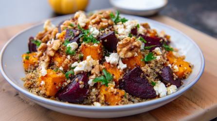 Eine Quinoa-Bowl mit Kürbis und Rote Bete sowie Walnüssen und Feta. Garniert mit frischen Kräutern.