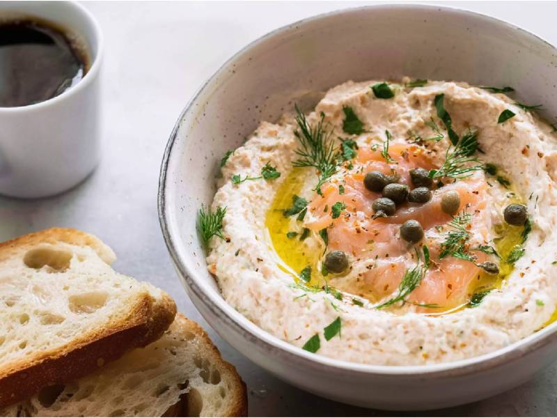 Schale mit Räucherlachs-Creme, zwei Scheiben Brot daneben, Tasse Kaffee im Hintergrund
